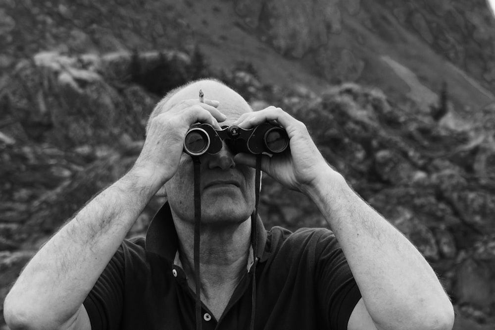 greyscale photo of man using binocular