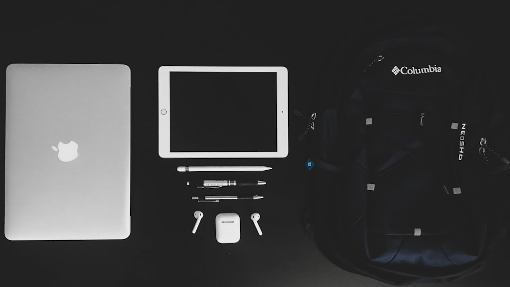 MacBook Air and white iPad near black Columbia backpack