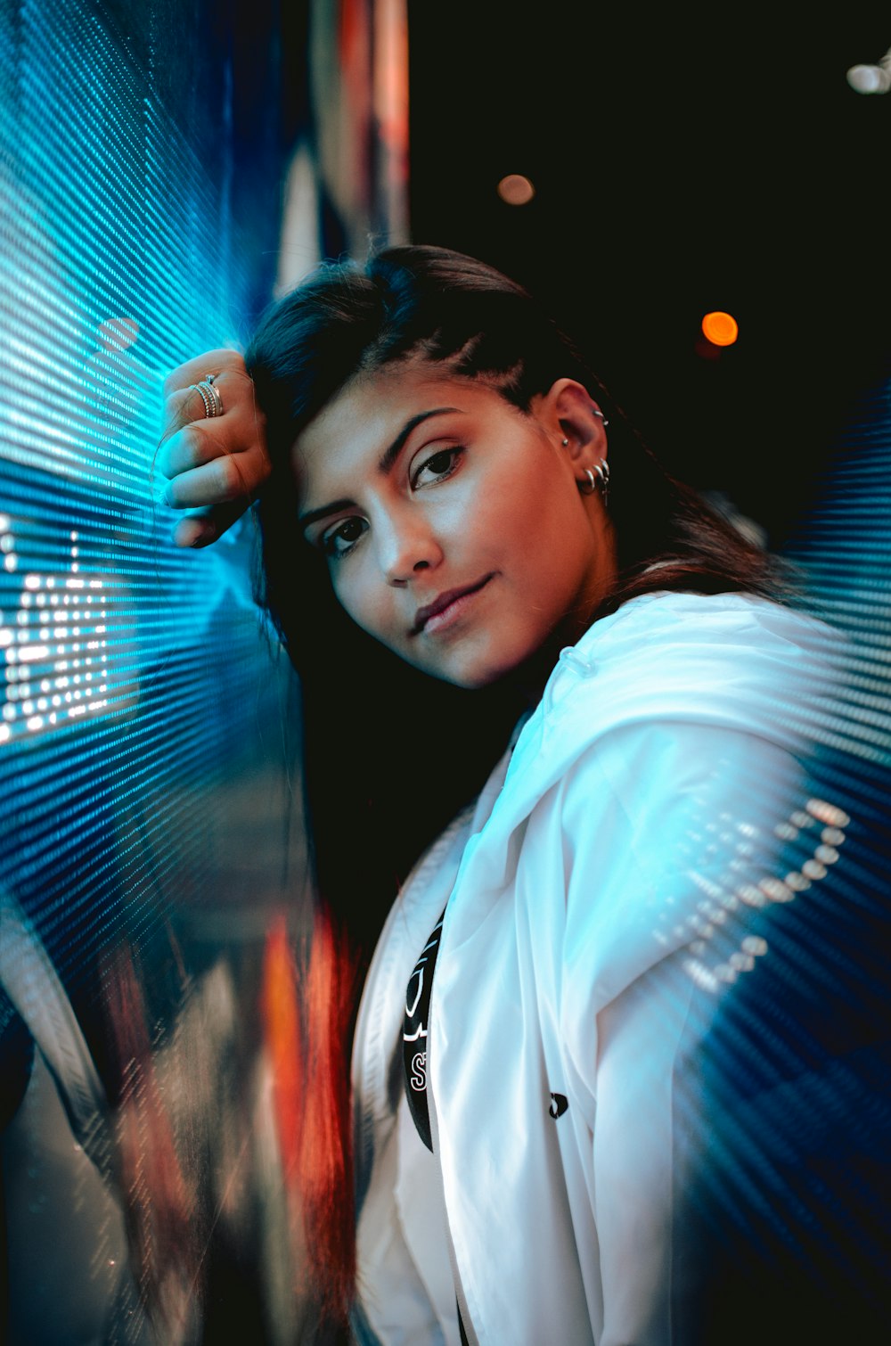 woman in white full-zip hoodie leaning on window during nighttime