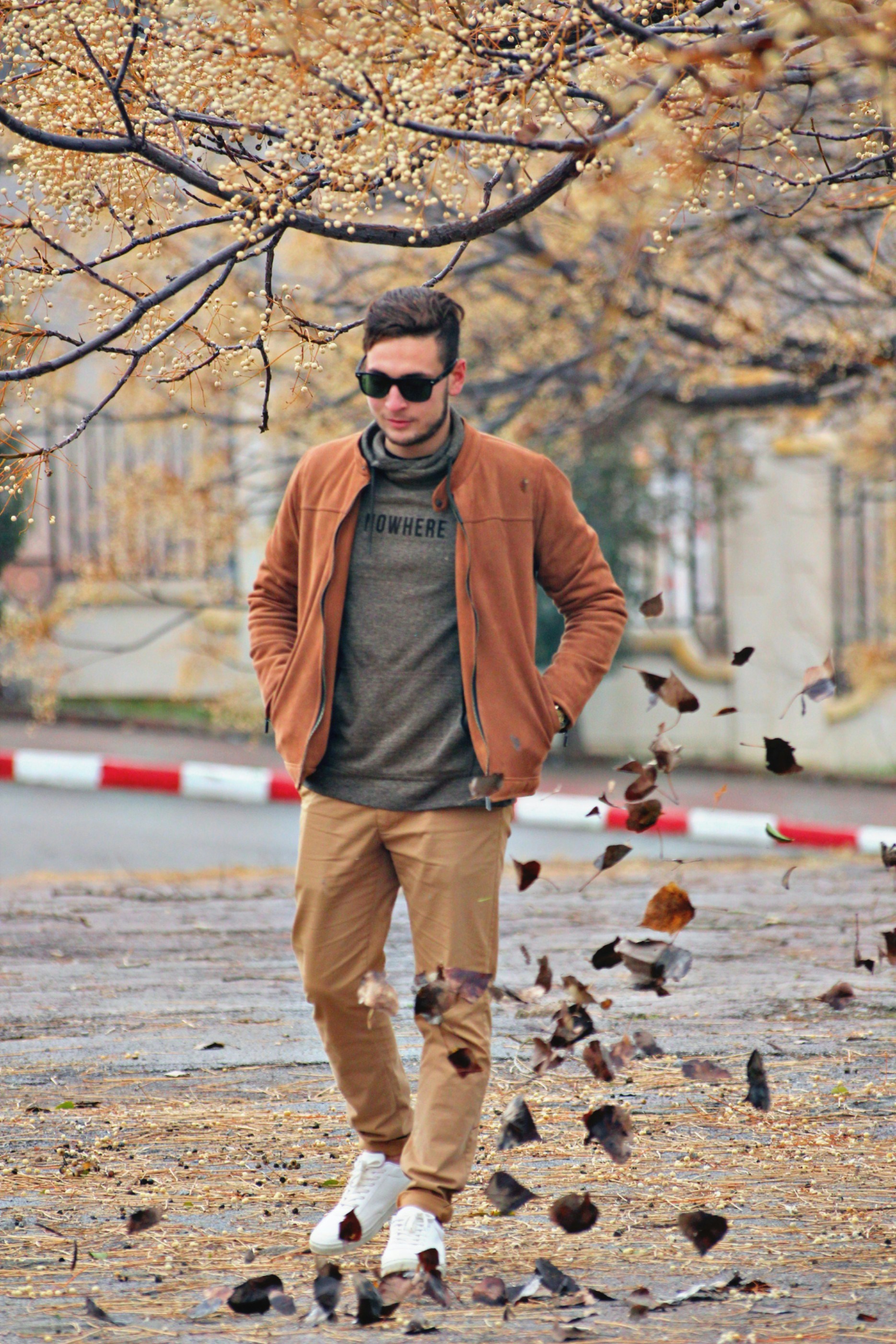 Man in a tan jacket and chinos walking in autumn