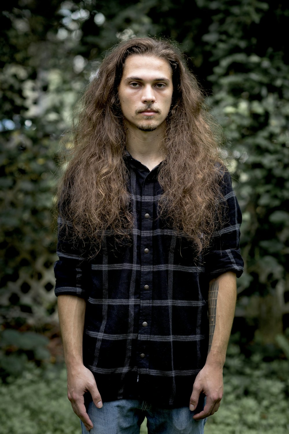 long-haired man wearing blue and grey plaid collared shirt