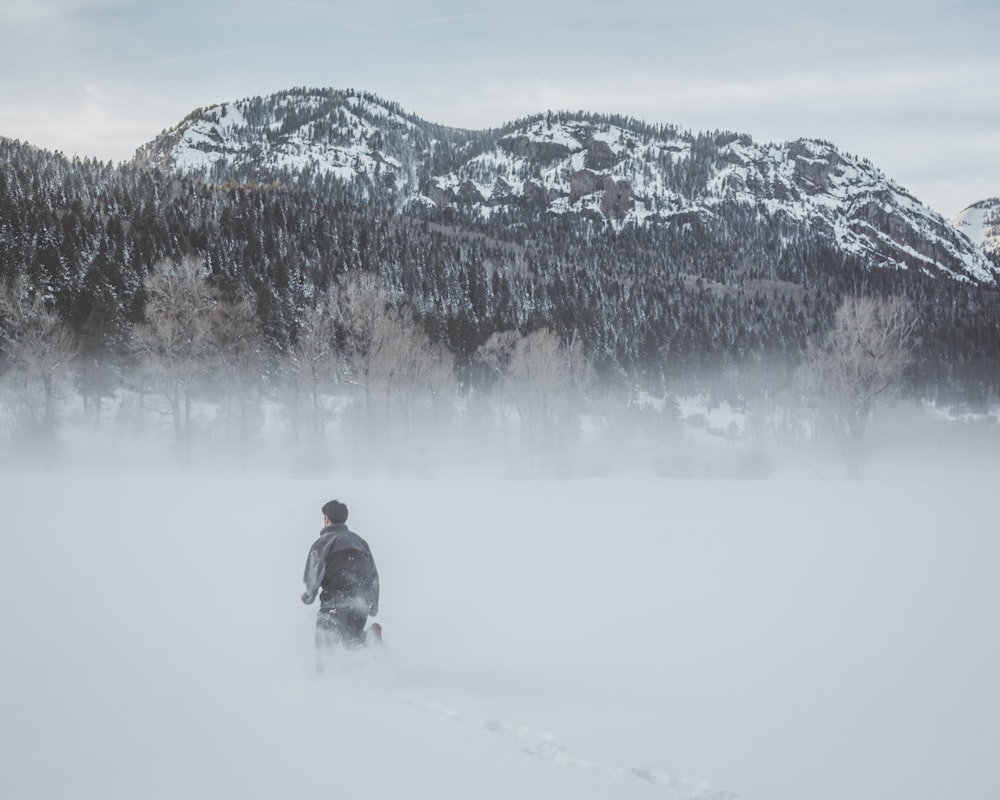 person walking on snow field near mountain range