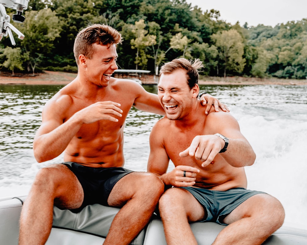 dois homens sentados no barco enquanto riem