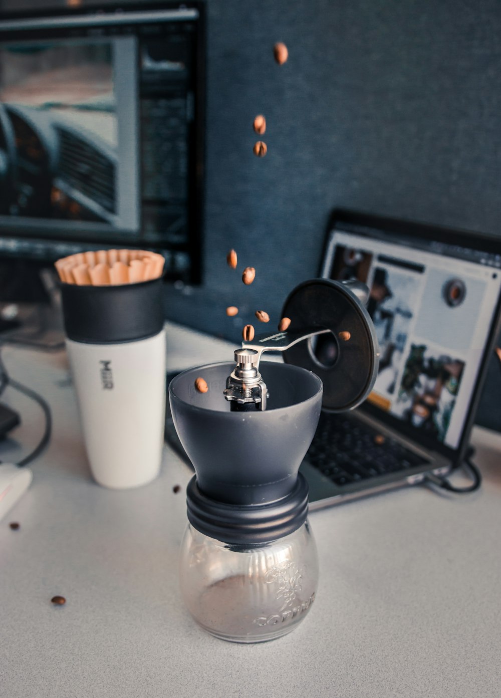 coffee grinder next to laptop computer and cup