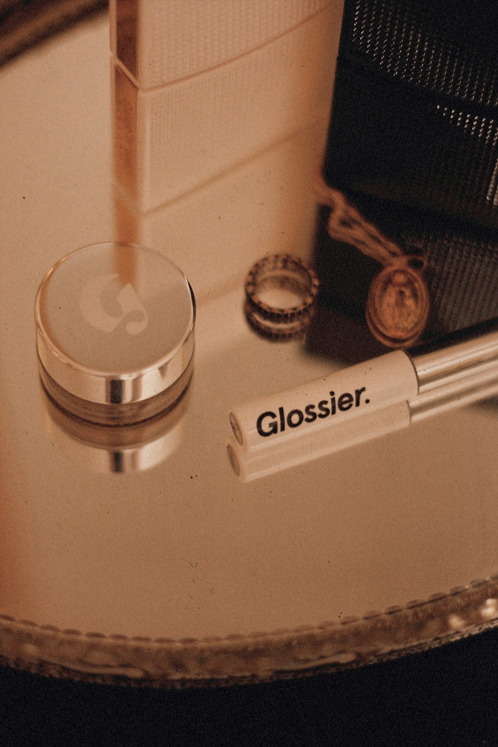 white and grey Glossier tube on table