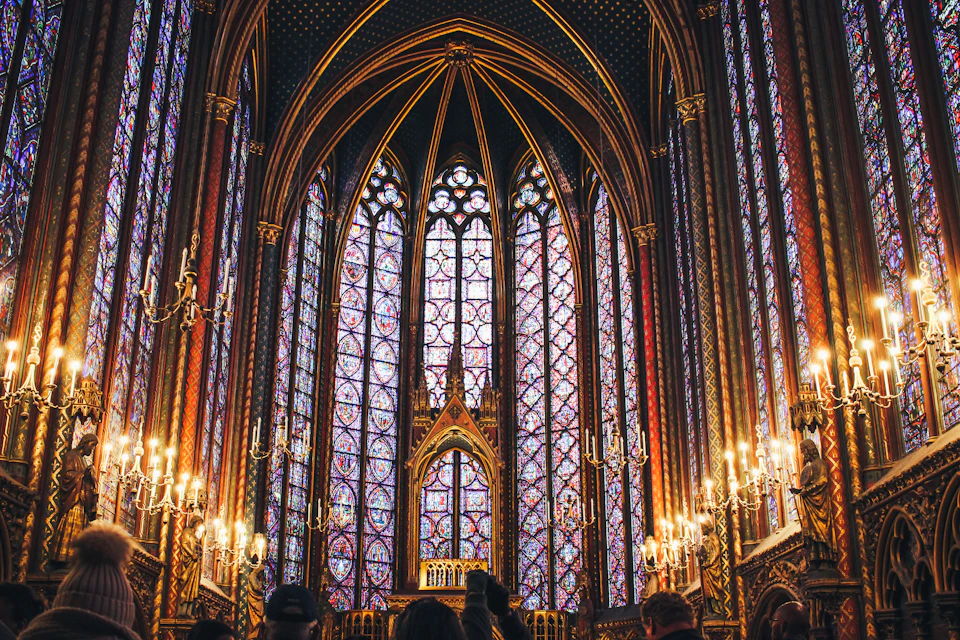 Gothic-style church interior with large stained glass windows and gold accents dominates the scene
