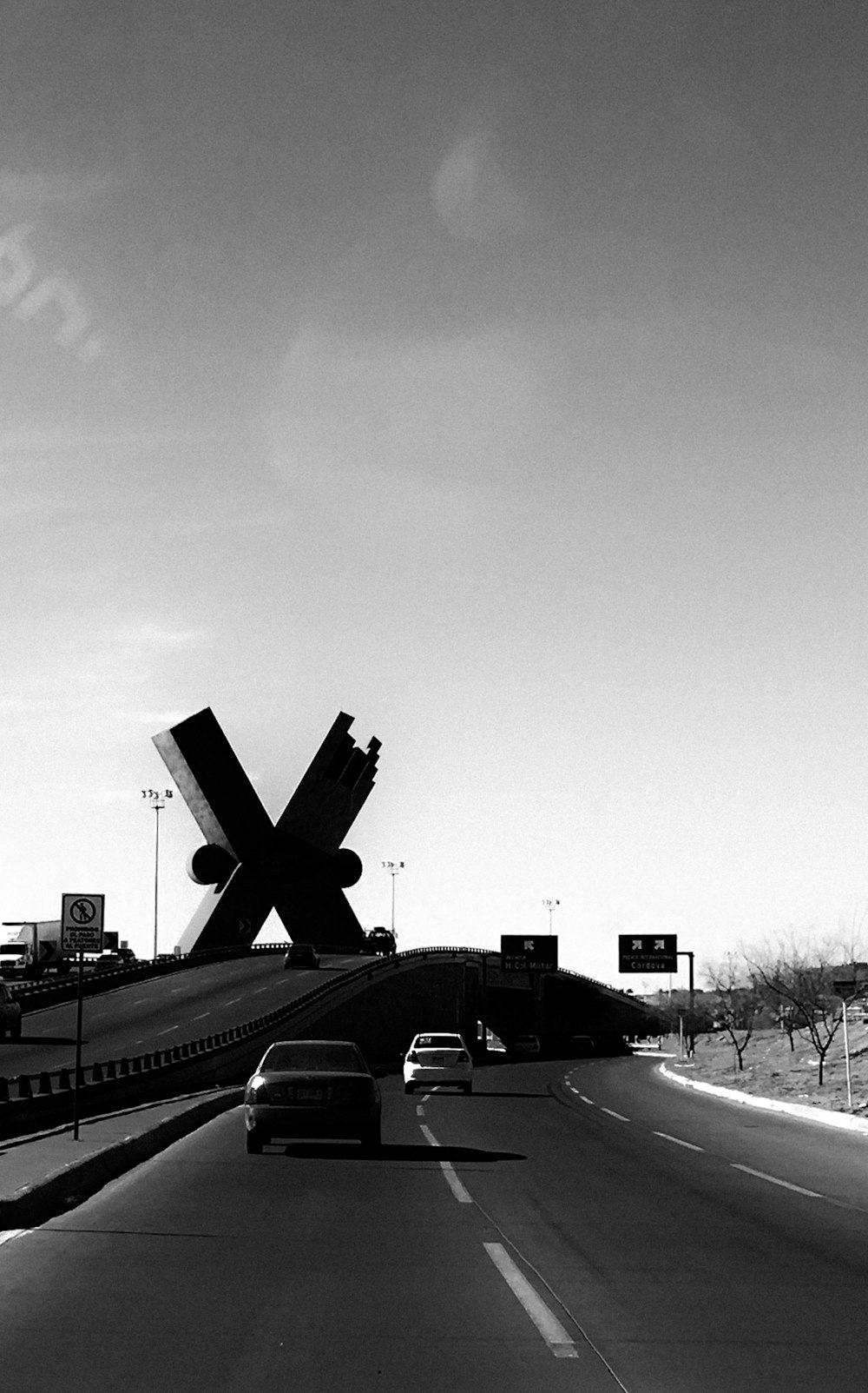 grayscale photography of two cars near concrete bridge