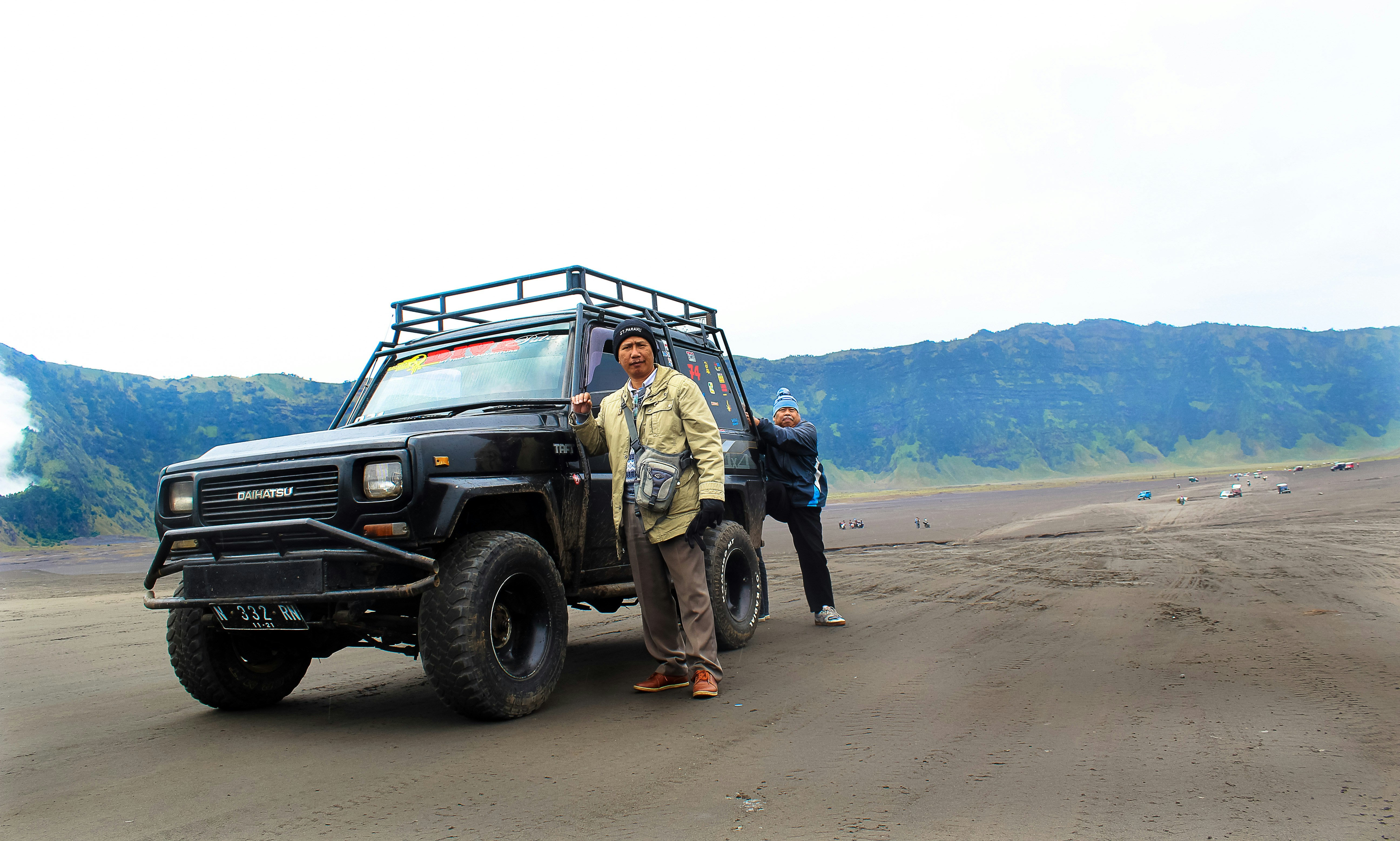 two men standing beside SUV