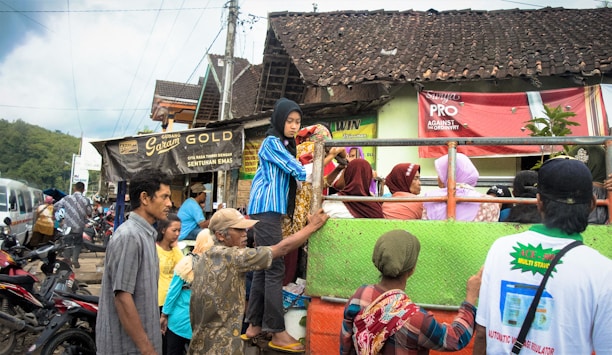 A colorful mobile social truck parked in a village square with people gathered around.