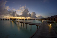 A panoramic sunset view over the turquoise Maldives lagoon dotted with luxury overwater villas.
