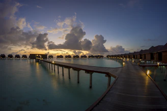 A panoramic sunset view over the turquoise Maldives lagoon dotted with luxury overwater villas.