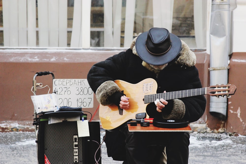 man playing with guitar near building