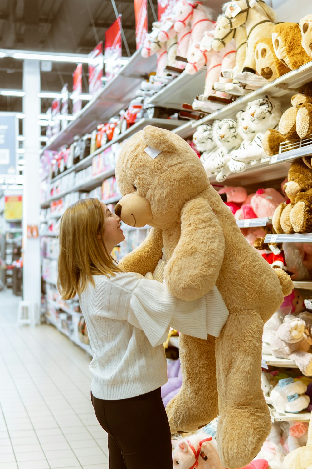 mujer que lleva un juguete de peluche de oso de tamaño natural