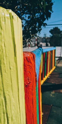 Painter carefully applying a fresh coat of paint to a wooden fence in a sunny Christchurch backyard.