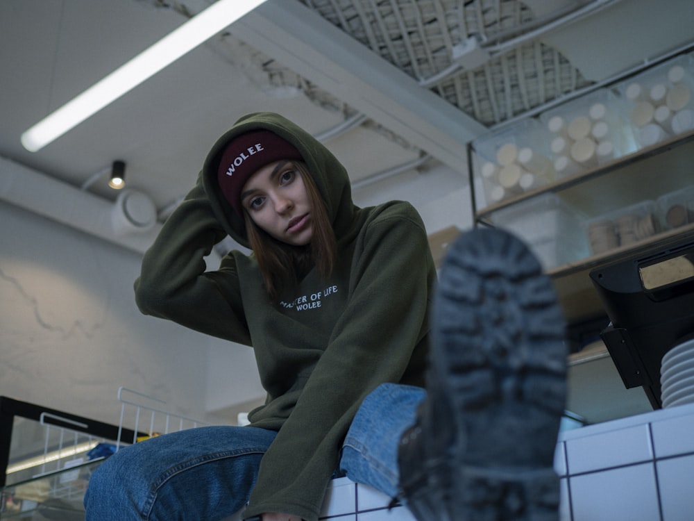 woman wearing green pullover hoodie and blue jeans