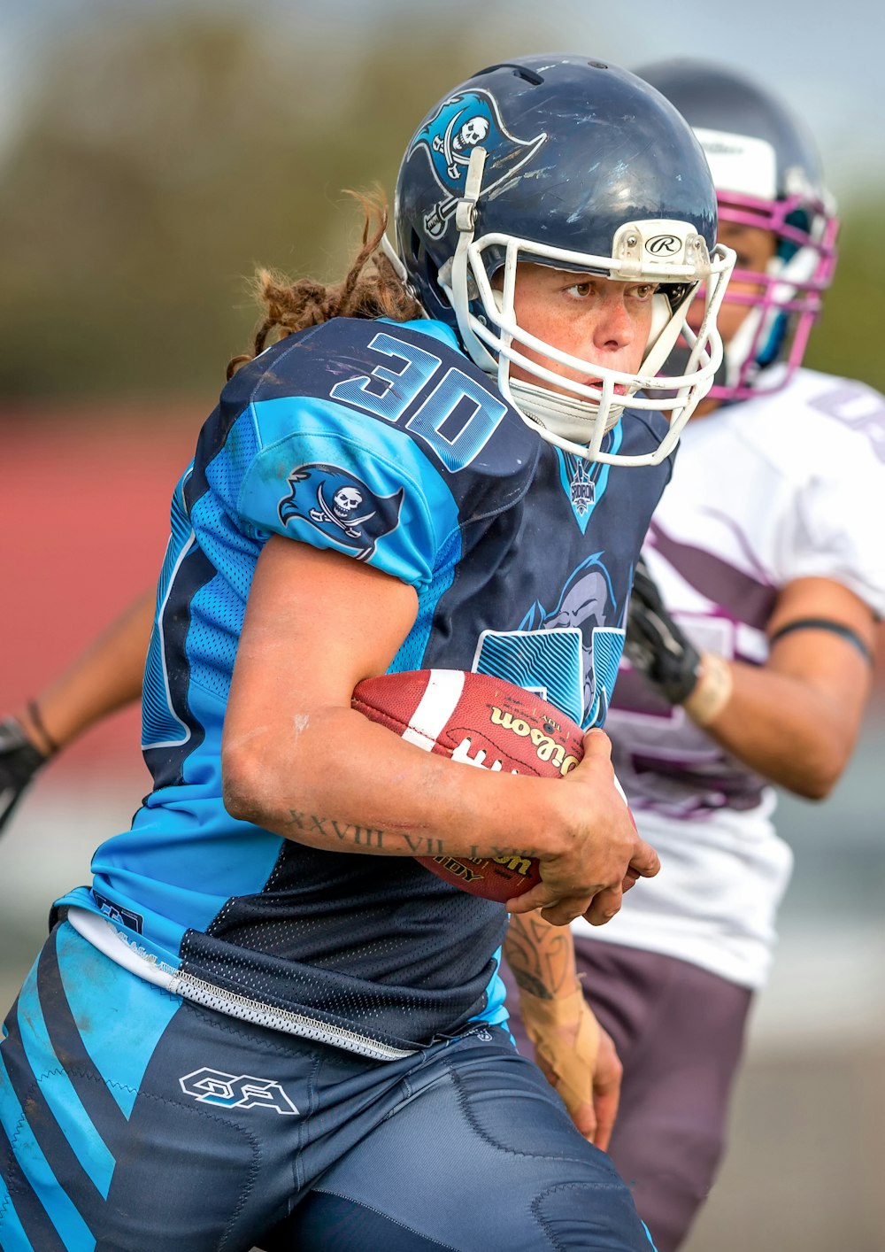 selective focus photography of woman in blue 30 jersey shirt holding brown football