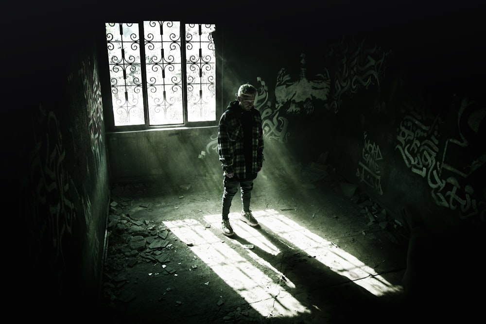 man in black and white winter jacket standing inside empty room during daytime