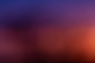 A blurred, colorful gradient blending softly into a dark void.
