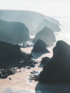 grayscale photography of rocky mountains and beach