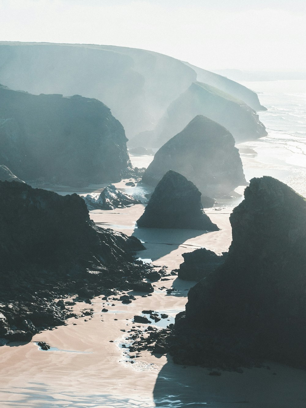 grayscale photography of rocky mountains and beach