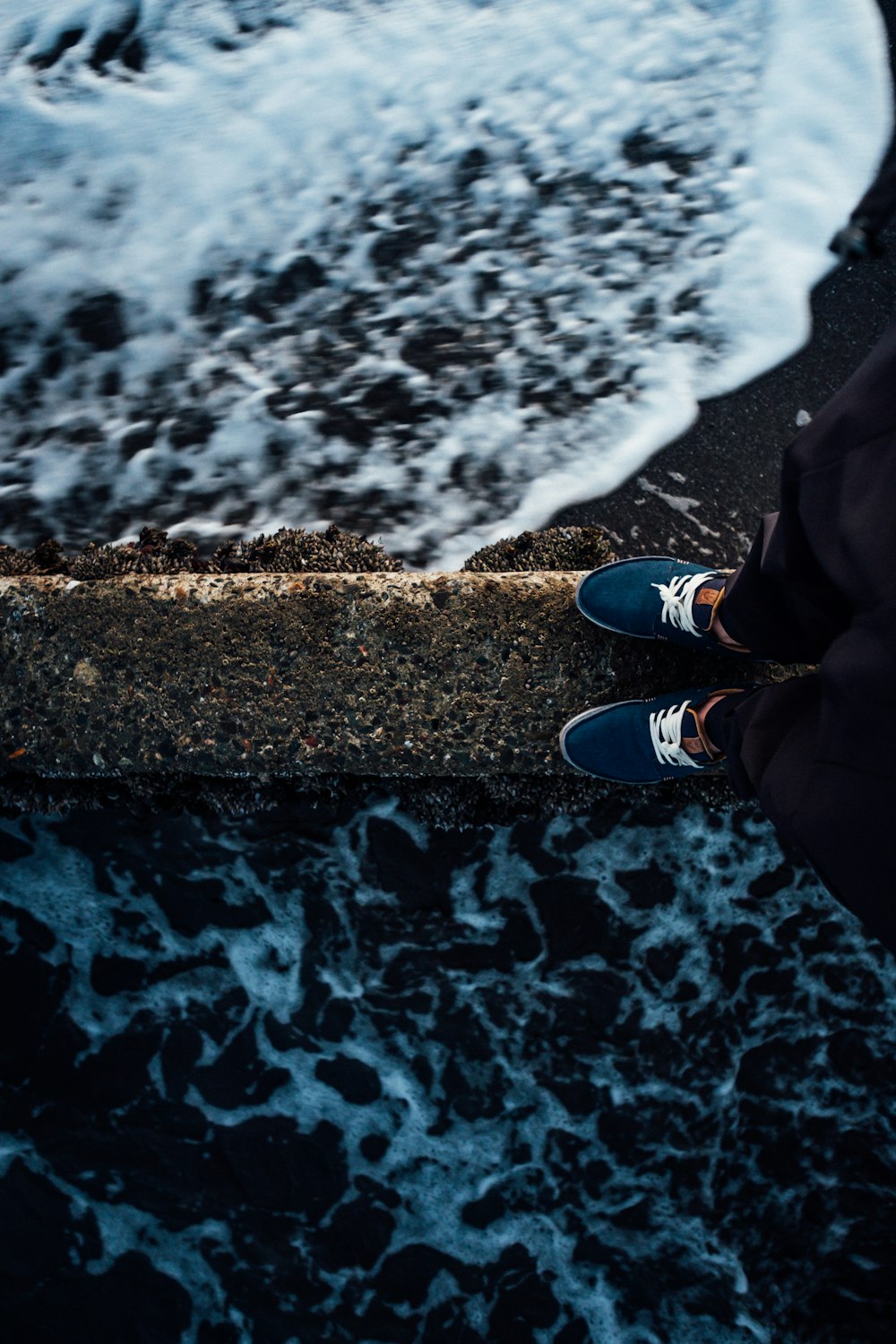 person standing on concrete surface near ocean