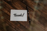 thanks! paper and black pen on wood surface