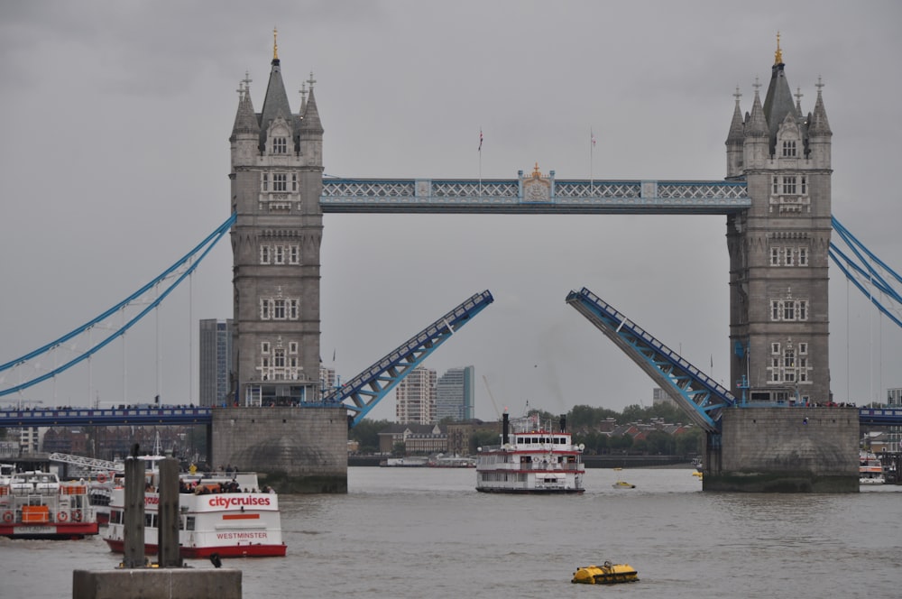 white ferry passing under tower bridge