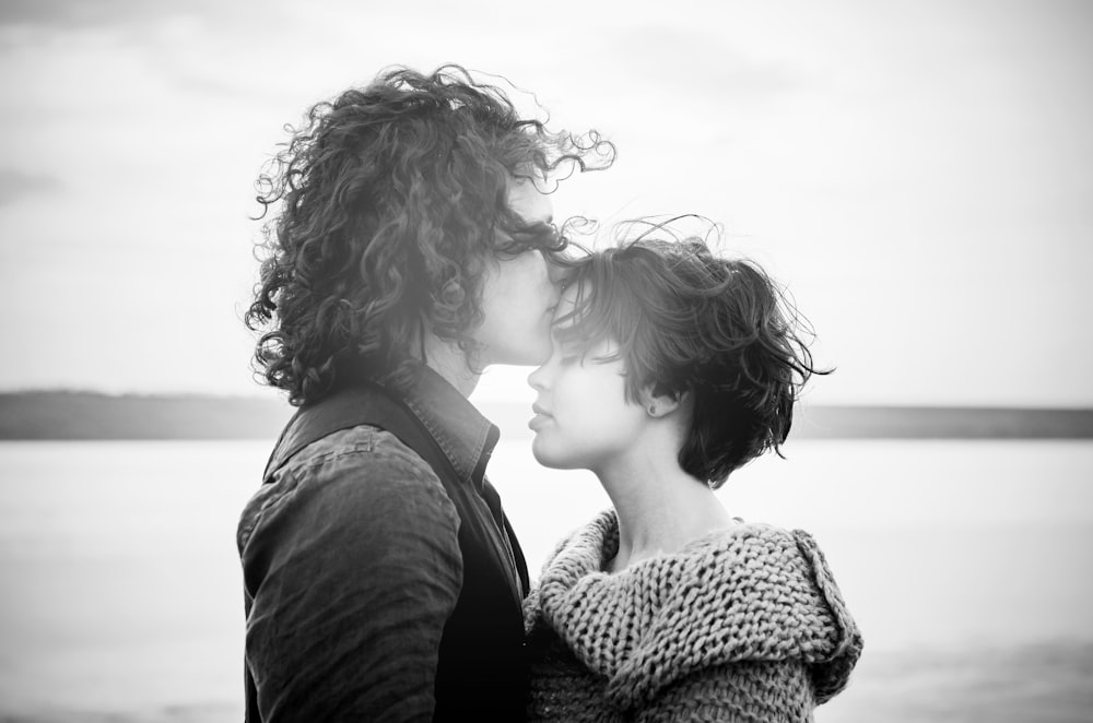 niveaux de gris d’un homme embrassant le front d’une femme