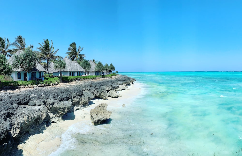 Felsiger Strand mit weißen Hütten unter strahlend blauem Himmel