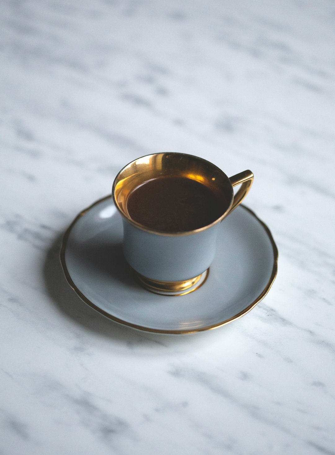 white and gold-colored teacup with saucer