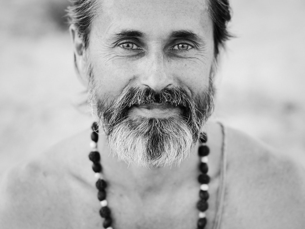 man in beads necklace grayscale photography