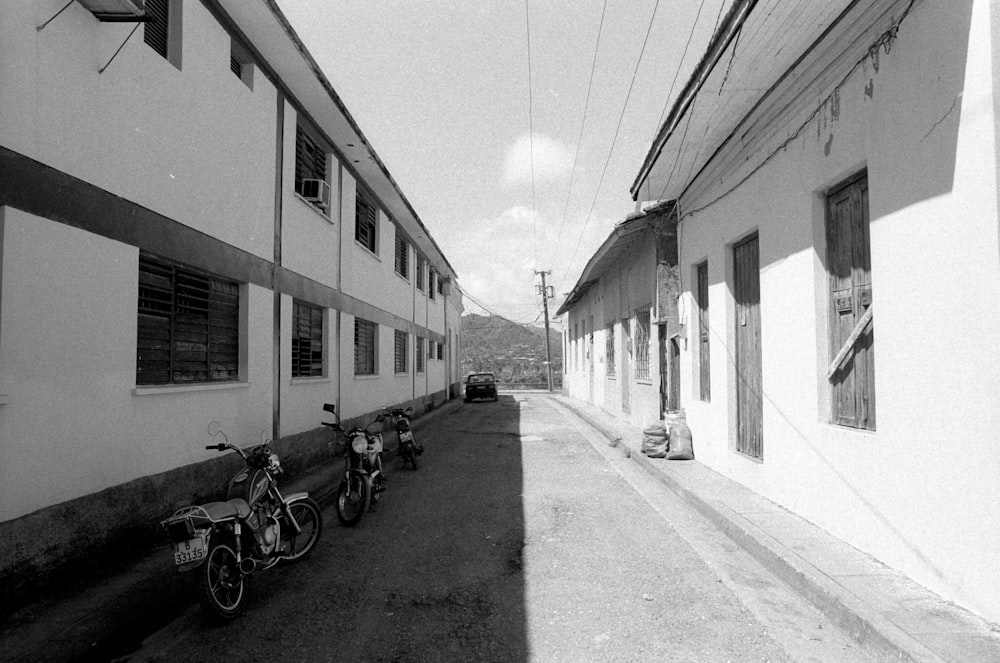 motorcycles parked on roadside during daytime greyscale photography