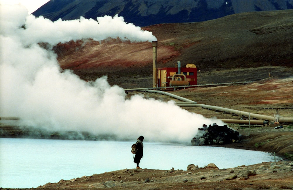 person standing near body of water and smoke