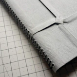 Close-up of a textured fabric folder with a stitched logo, placed on a cozy workspace.
