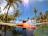 Smiling woman relaxing by a sparkling clear pool under a sunny sky with palm trees.