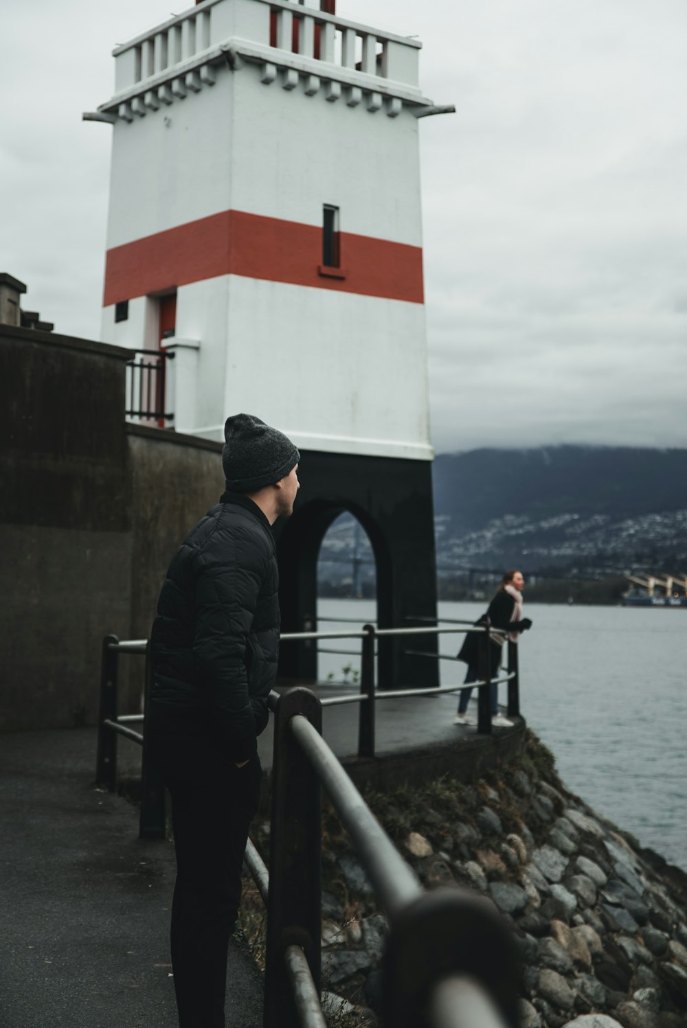 man standing near lighthouse beside sea