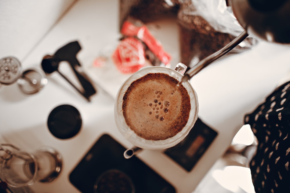 top view photography of person pouring coffee on white ceramic cup