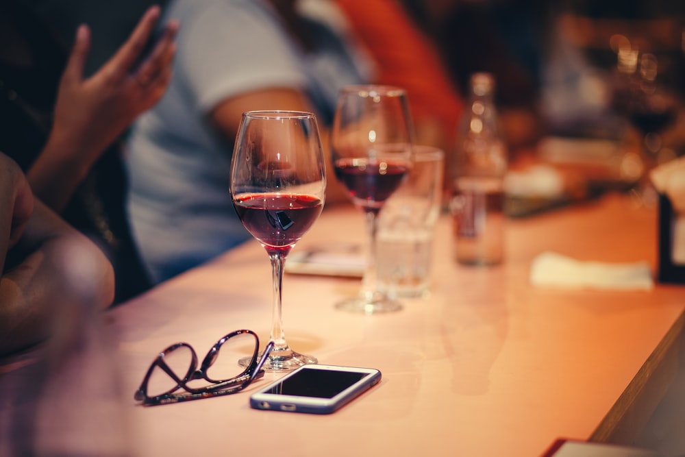 personas sentadas cerca de copas de vino en una mesa de madera marrón