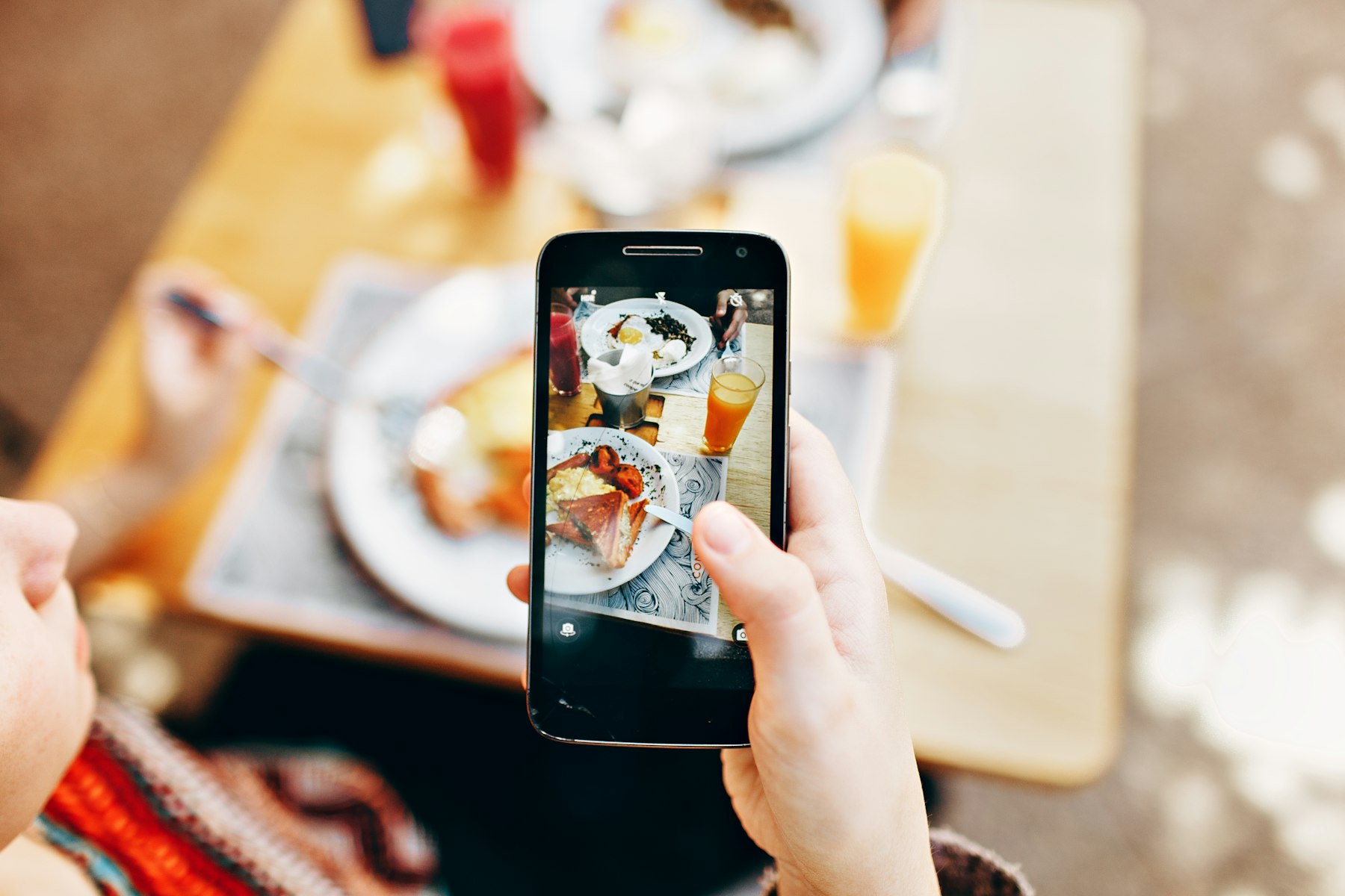 Person taking a photo of food on their phone at a restaurant