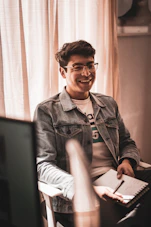 A friendly young person holding a notebook, smiling and ready to help