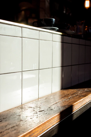 A cozy kitchen countertop gleaming with a soft beige quartz surface, sunlight streaming through a nearby window.