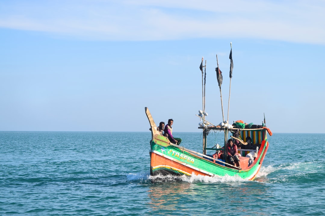 three people riding on green and red boat during daytime