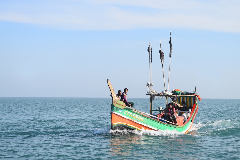 three people riding on green and red boat during daytime