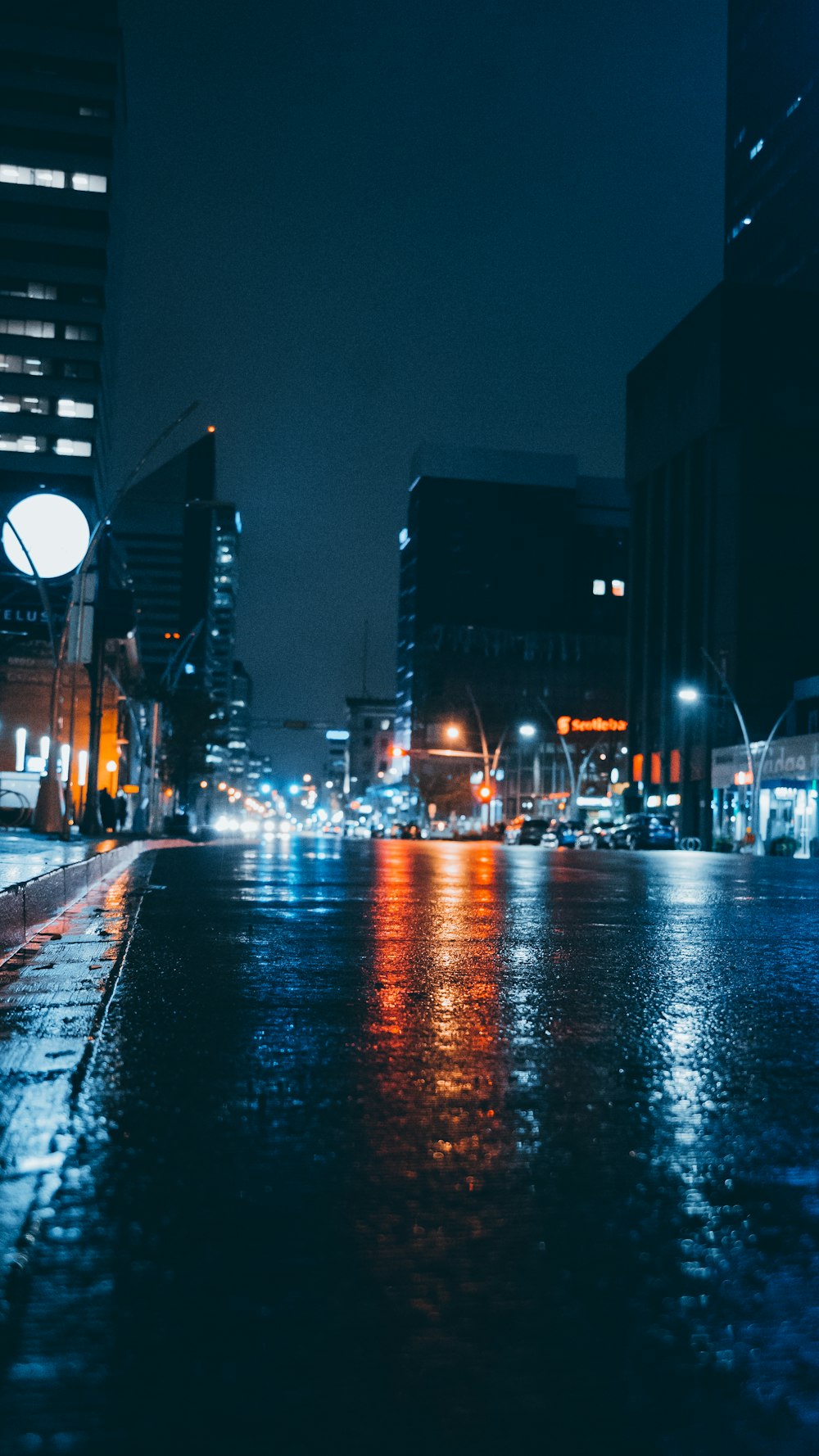 夜間の高層ビル近くの濡れた灰色の道路