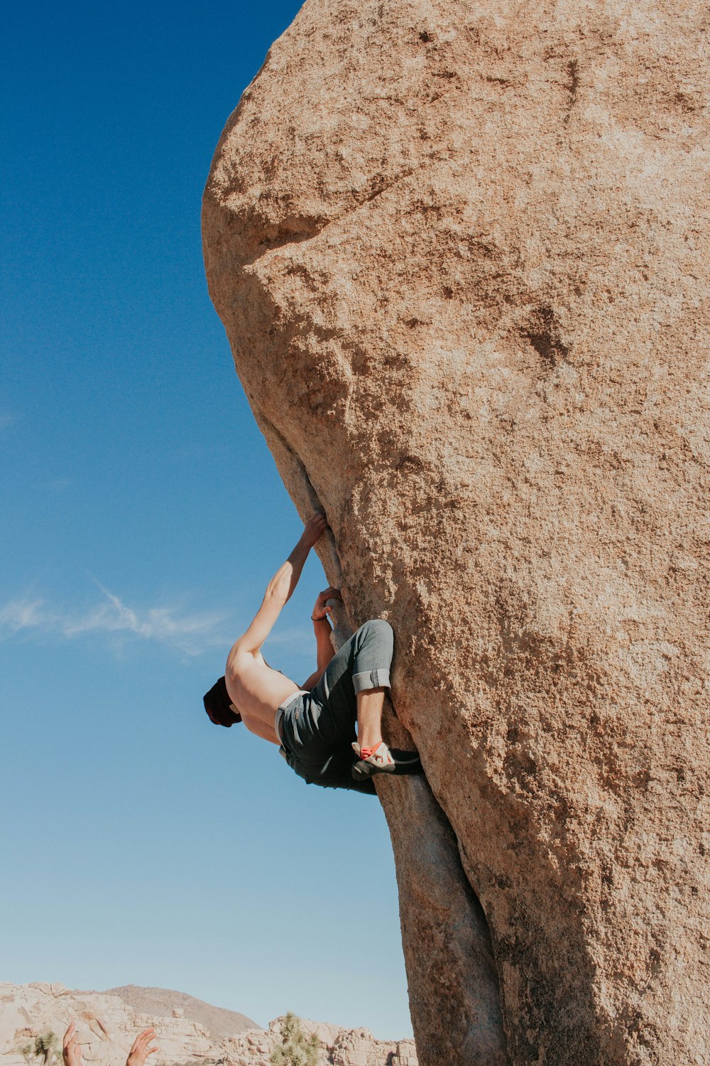 man climbing brown rock