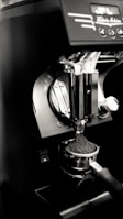 An espresso machine's portafilter is being filled with freshly ground coffee. The setup is sleek and modern, featuring a metallic finish with some controls visible at the top.