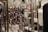 The image features a close-up view of a metallic, reflective, geometric structure with square shapes. In the background, there are blurred images of clothing items, including a black garment and other patterned clothing.