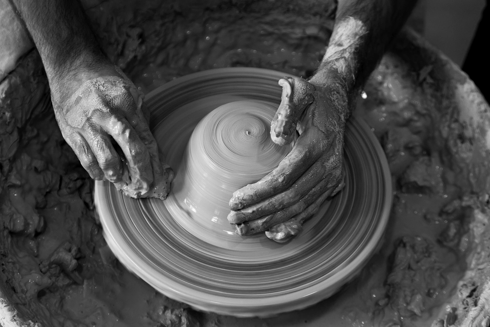 Hands shaping clay on a pottery wheel