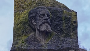 Brumble, the wise and grumpy mentor, perched on a mossy rock surrounded by ancient runes.