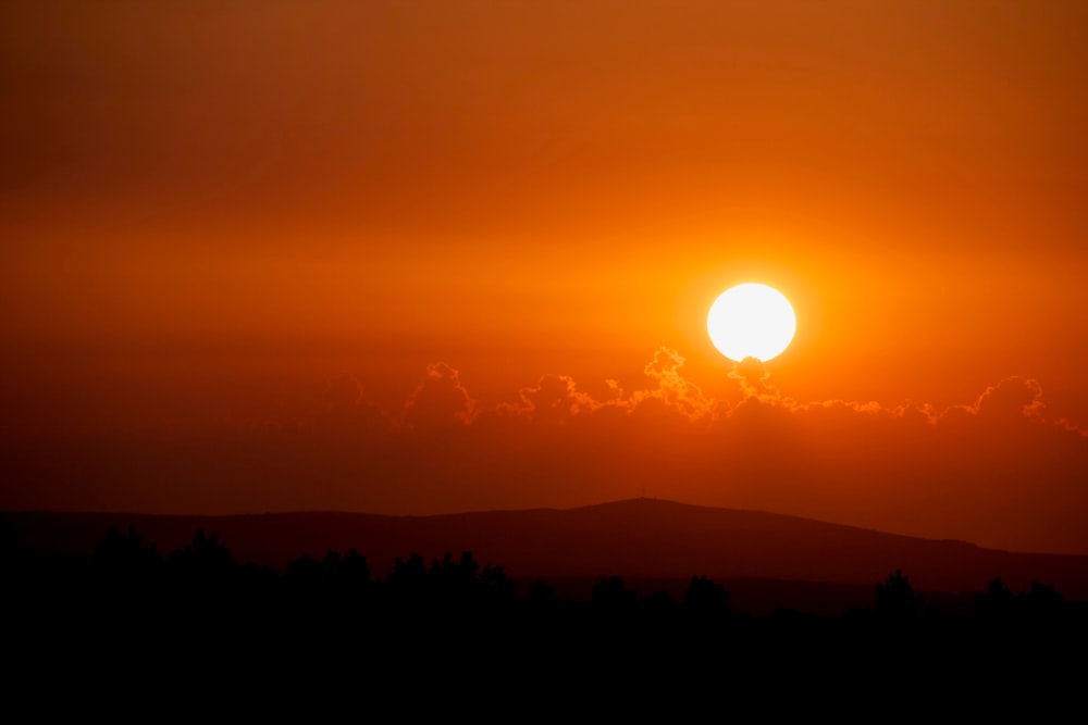 Pôr do sol laranja acima da silhueta da montanha